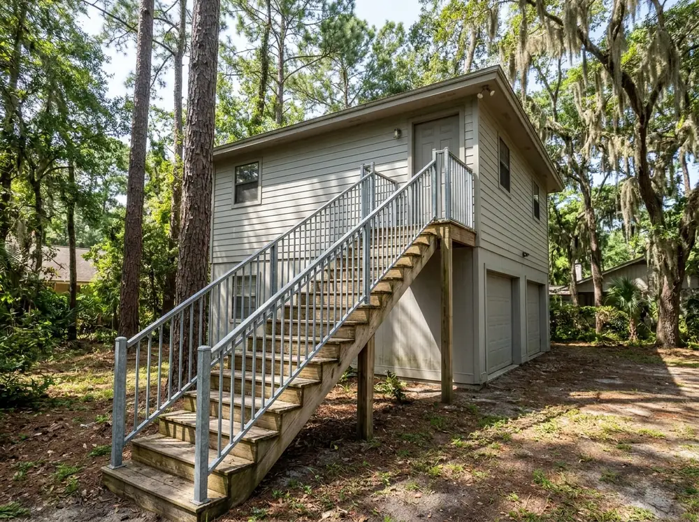 Galvanized metal railing running up a wooden exterior staircase to a second-story door
